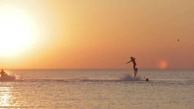 Silhouette of a Man Having Fun on Flyboard in the Sea at Sunset Background