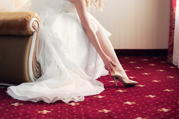 Fototapeta premium the bride puts on elegant wedding shoes.