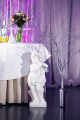 sculpture of an angel in a wedding decor. Violet illumination.