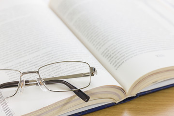 Close up glasses and a book on the desk