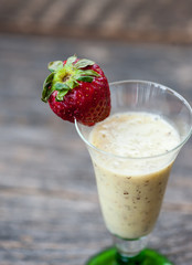 Kiwi and banana smoothie in a glass with strawberries