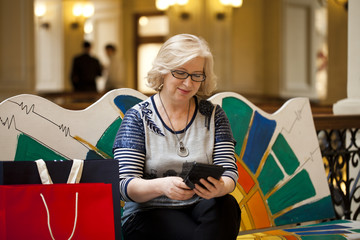Elderly woman sitting on a bench with tablet