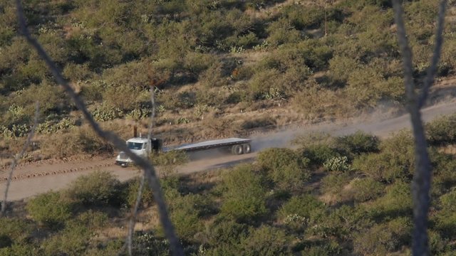 Tractor trailer trucks pass by on a dirt road