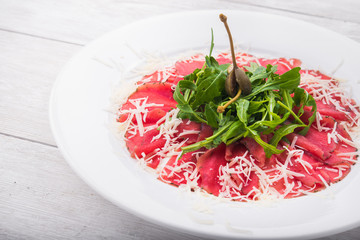 white dish with carpaccio and cheese