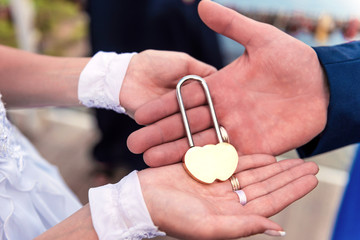 Romantic hands holding heart shaped lock.