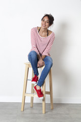 student vacation smile - thrilled beautiful ethnic girl sitting on a stool enjoying free time,...