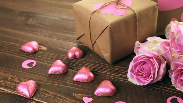 Pink roses and gift wrapped in recycled paper on rustic wood table