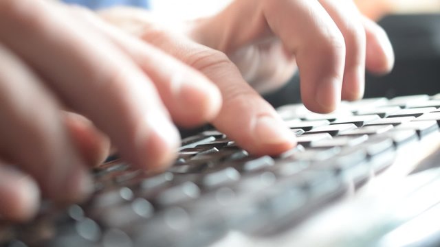 Close-up of male hands typing on black keyboard