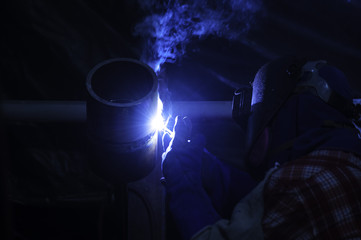 Worker welding pipes using tig welder