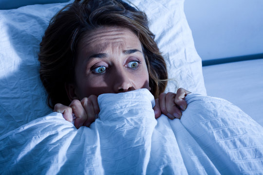 femme au lit cach&eacute;e sous les draps apeur&eacute;e
