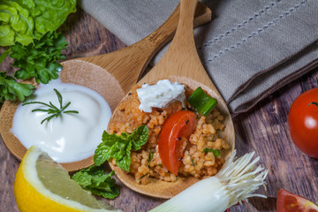 Bulgursalat mit Joghurt, angerichet auf Holzlöffeln auf altem Tisch