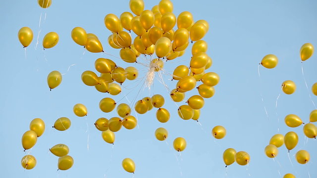 a lote of yellow balloons fly in the blue sky in summer day
