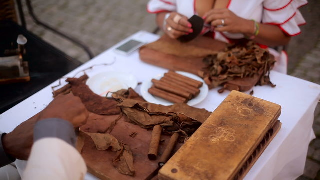 the hands of Cubans, men and women wrapped cigars on the table