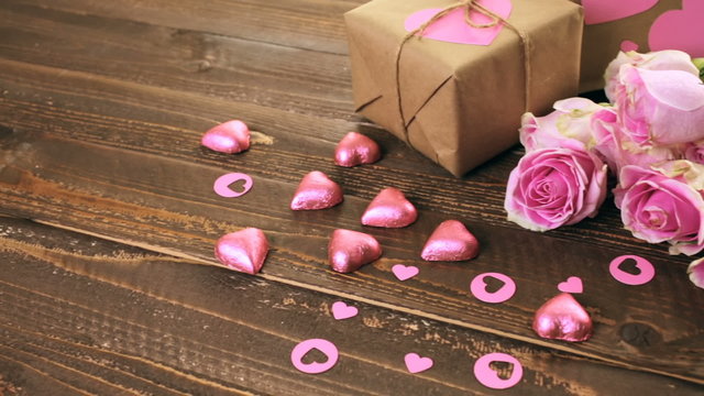 Pink roses and gift wrapped in recycled paper on rustic wood table