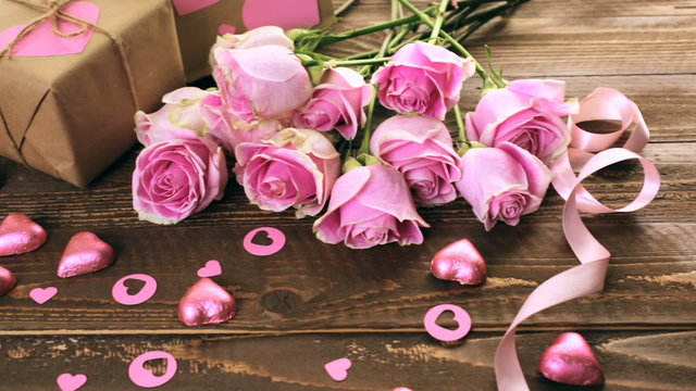 Pink roses and gift wrapped in recycled paper on rustic wood table