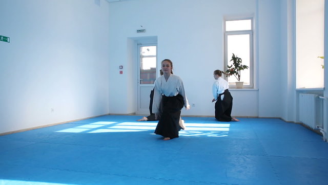 Three girls in black hakama practice Aikido on martial arts training