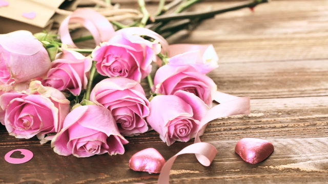 Pink roses and gift wrapped in recycled paper on rustic wood table