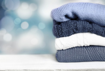 Pile knitted winter autumn clothes on wooden background.
