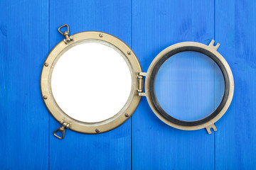 Brass porthole in blue wooden wall, opened, with clipping path