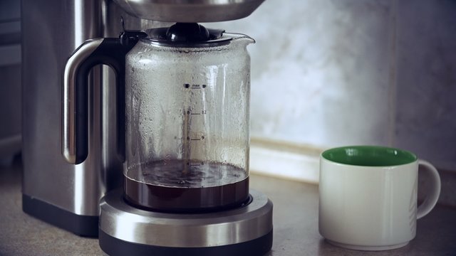 Close-up shot of coffee brewing in coffee maker and flowing in to carafe