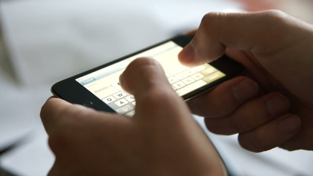 Man using his smartphone touchscreen device to type a text message with his fingers.