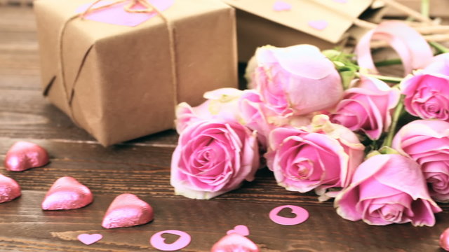 Pink roses and gift wrapped in recycled paper on rustic wood table