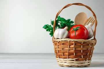 wicker basket with parsley and tomato with garlic on wooden white background