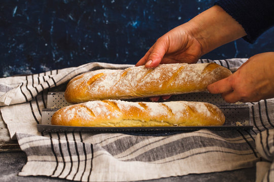 Hot french baguettes. Holding of Fresh homemade baguette over on a linen cloth.