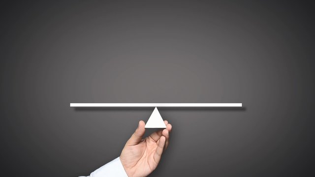 Gender equality concept. Hand holding balance with male and female figures. The male figure outweighs the female figure