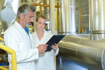 Man and woman in factory holding clipboard