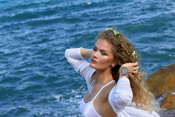 Fototapeta na wymiar pretty curly girl portrait with flowers in hear, sea view