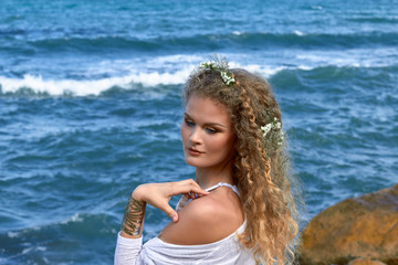  pretty curly girl portrait with flowers in hear, sea view