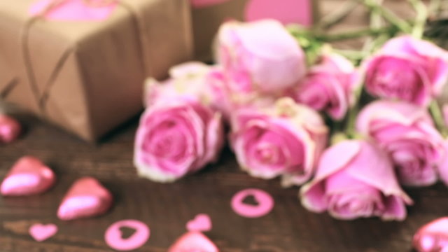 Pink roses and gift wrapped in recycled paper on rustic wood table