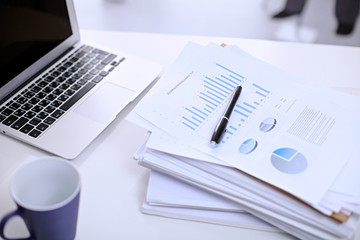 .Office workplace with a laptop and financial documents on the light reflecting table