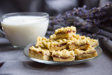 Cake with jam is on the glass saucer with milk and lavender.