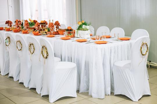 Decorative wreath on white chairs. Chairs and table covered with