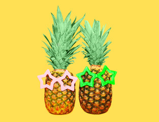 Two pineapple with sunglasses on yellow background, colorful ana