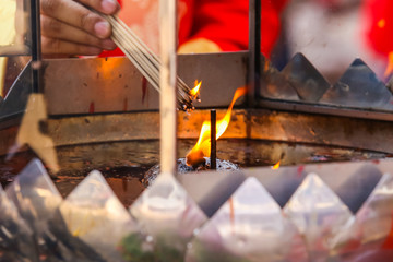 Hand and the fire candle and the burning stick , burning candle and burning incense.