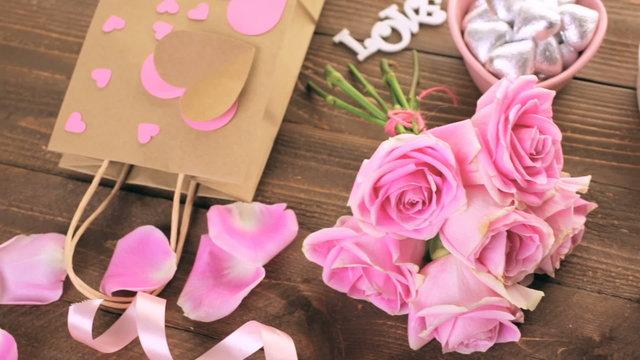 Pink roses with chocolates on rustic wood table