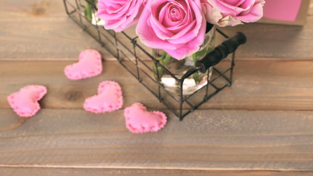 Pink roses in jars on rustic wood table.