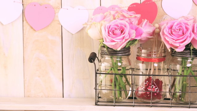 Pink roses in jars and gifts on rustic wood shelf for Valentines DAy