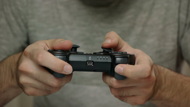 Man playing with a videogame controller in his hands. Focus on the controller
