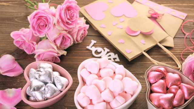 Pink roses with chocolates on rustic wood table