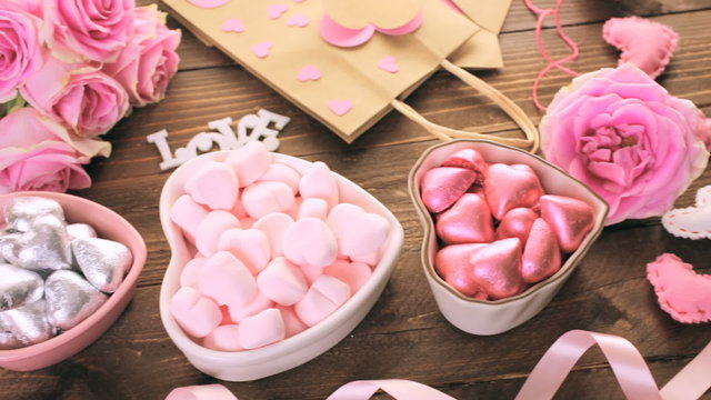 Pink roses with chocolates on rustic wood table