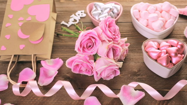 Pink roses with chocolates on rustic wood table