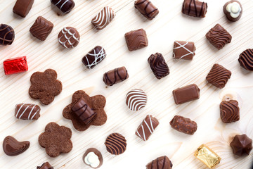 abundance of chocolates on a light wooden background close up, the top view