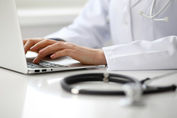 Female doctor typing on laptop, close up