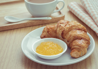 Croissant with jam on plate and coffee cup, Filtered image