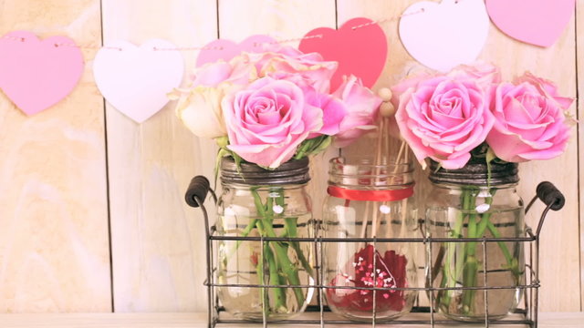 Pink roses in jars and gifts on rustic wood shelf for Valentines DAy