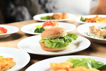Burger and a plate of delicious dishes on the table 